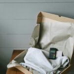 Cardboard box containing a folded shirt and a payment terminal, perfect for e-commerce themes.