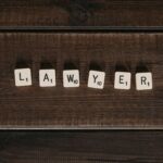 Close-up of scrabble tiles spelling 'lawyer' on a dark wooden surface.